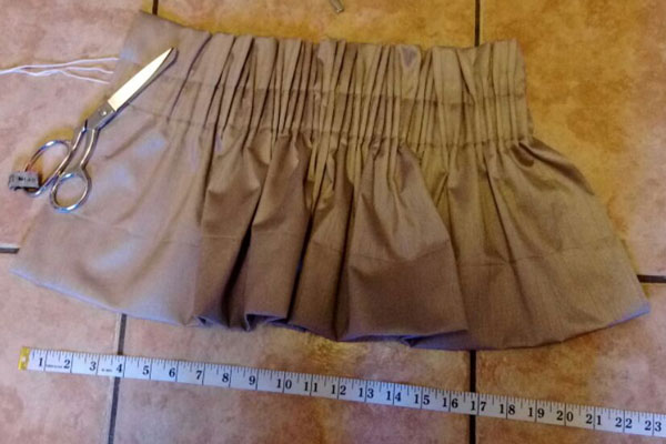 A pencil pleat heading gathered on a curtain, with a tape measure beside it